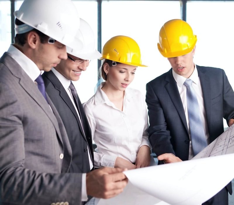 Equipo de arquitectos e ingenieros observando los planos de Construcción.
